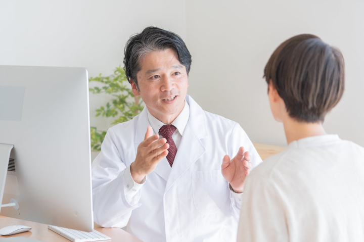 インプラント治療中に妊娠がわかった患者が歯科医に相談しているイメージ