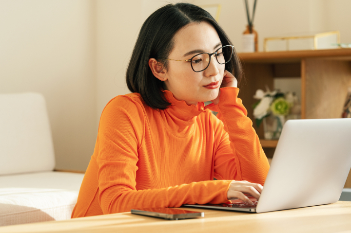 頬杖をついてパソコンを見る女性