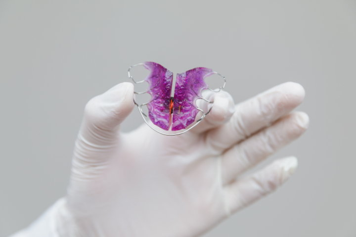 床矯正の装置を見せる歯科医師の手