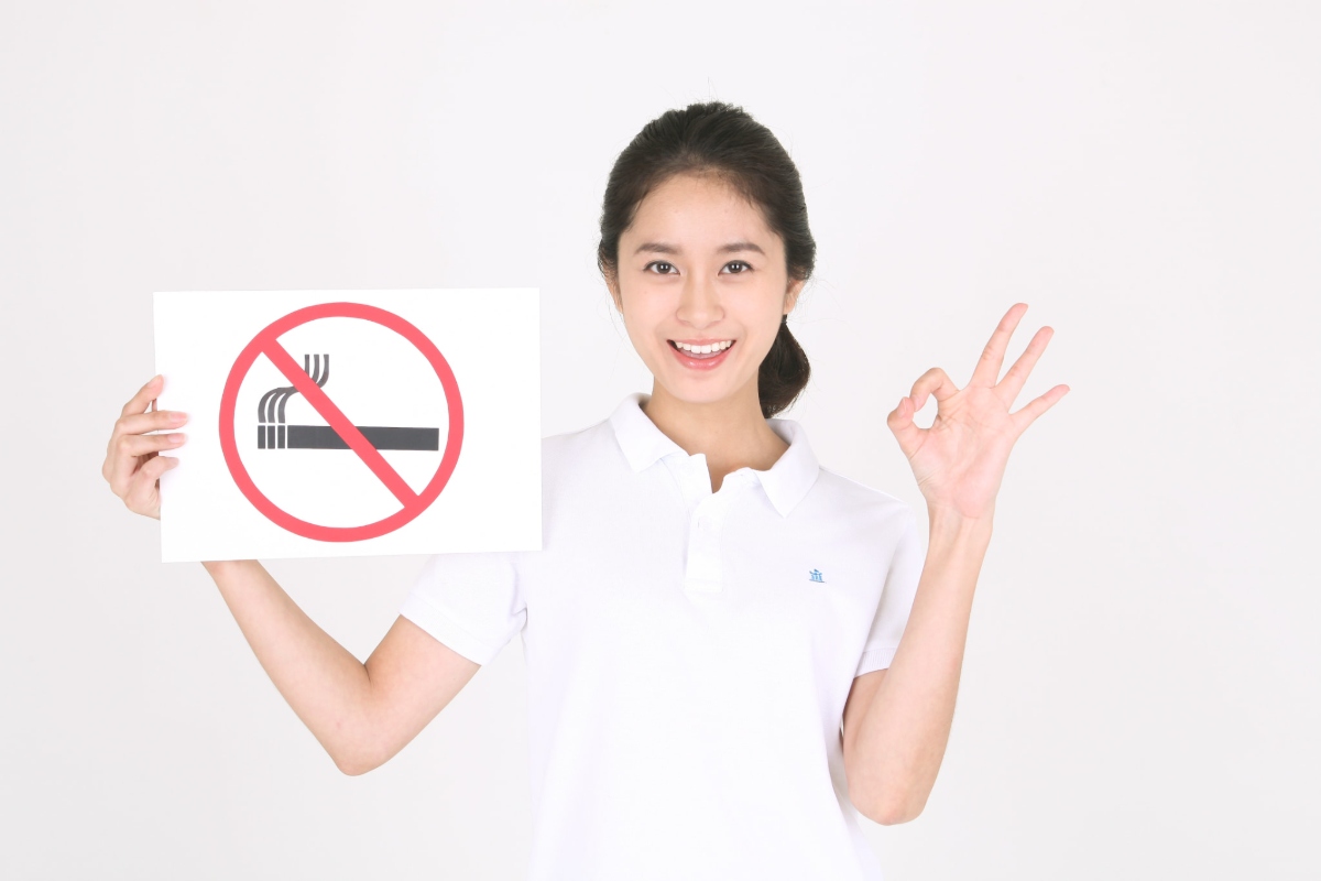禁煙マークを手にOKサインをする歯科衛生士